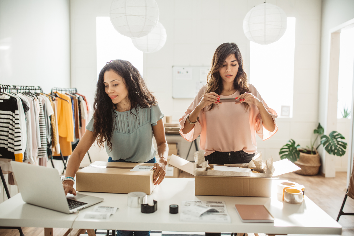 small business owners taking pictures of packages and using laptop to promote their clothing business